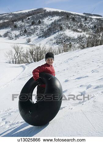 Stock Photograph - Boy carrying tube in snow. Fotosearch