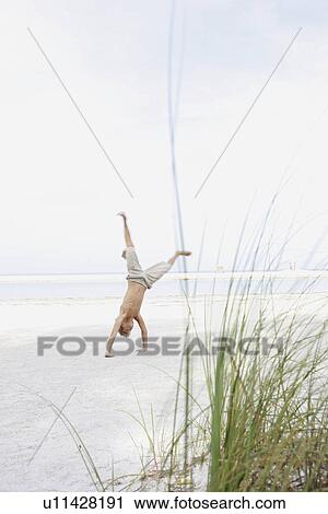 Boy doing cartwheel on beach View Large Photo Image Stock Image - Boy doing cartwheel on beach. Fotosearch