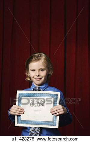 Stock Photograph - Boy holding certificate on stage. Fotosearch