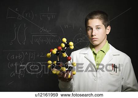 Stock Photo - Boy holding molecular model in front of blackboard . Fotosearch