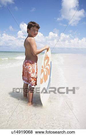 Boy holding skimboard in ocean View Large Photo Image Stock Photo - Boy holding skimboard in ocean. Fotosearch