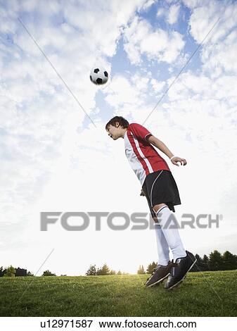 Stock Photo - Boy in uniform bouncing soccer ball off head. Fotosearch