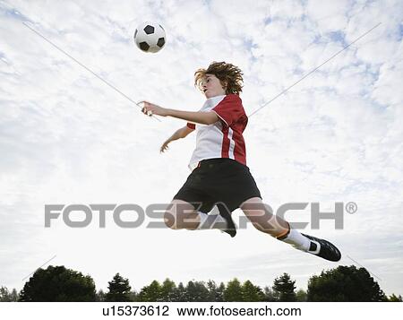 Boy jumping toward soccer ball in mid-air View Large Photo Image Stock Image - Boy jumping toward soccer ball in mid-air. Fotosearch
