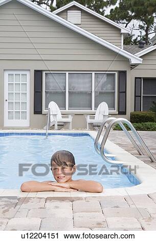 Stock Image - Boy leaning on edge of swimming pool. Fotosearch