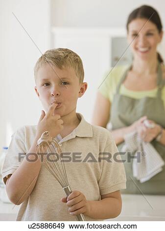 Stock Photo - Boy licking finger and holding whisk. Fotosearch
