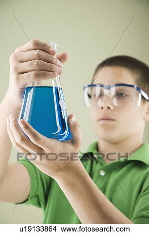 Picture - Boy looking at beaker of liquid. Fotosearch