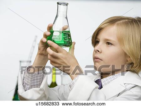 Stock Image - Boy looking at beaker of liquid. Fotosearch