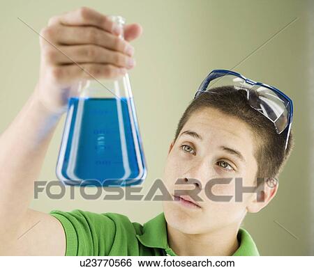 Stock Photograph - Boy looking at beaker of liquid. Fotosearch