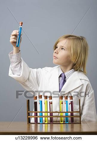 Stock Photograph - Boy looking at vial of liquid. Fotosearch