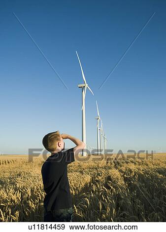 Stock Photo - Boy looking up at windmills on wind farm. Fotosearch