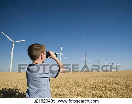 Stock Photography - Boy on wind farm looking through binoculars. Fotosearch