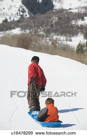 Stock Photo - Boy pulling brother in sled. Fotosearch