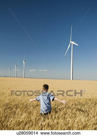 Picture - Boy running through field on wind farm. Fotosearch