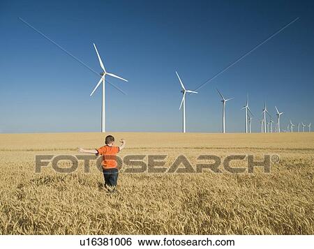 Boy running through field on wind farm View Large Photo Image Stock Photograph - Boy running through field on wind farm. Fotosearch