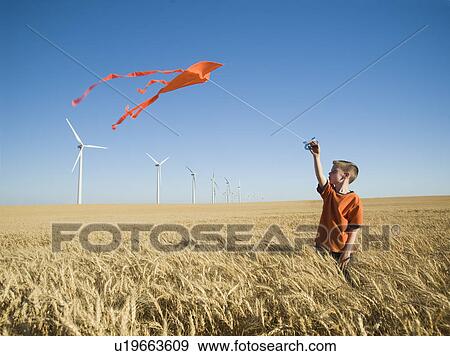 Stock Photo - Boy running with kite on wind farm. Fotosearch