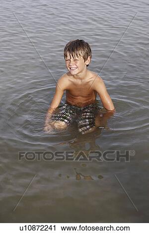 Boy sitting in shallow water View Large Photo Image Stock Image - Boy sitting in shallow water. Fotosearch