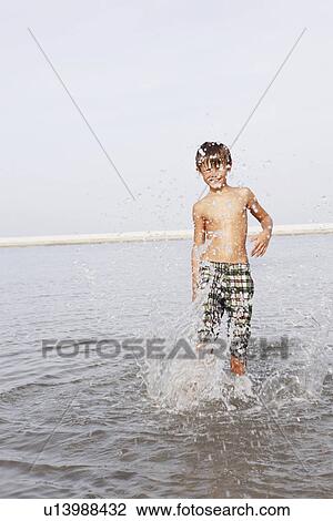 Stock Image - Boy splashing in ocean. Fotosearch