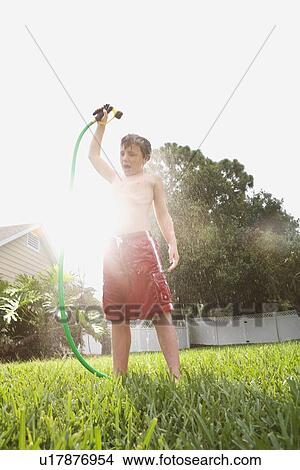 Boy spraying himself with hose in backyard View Large Photo Image Picture - Boy spraying himself with hose in backyard. Fotosearch