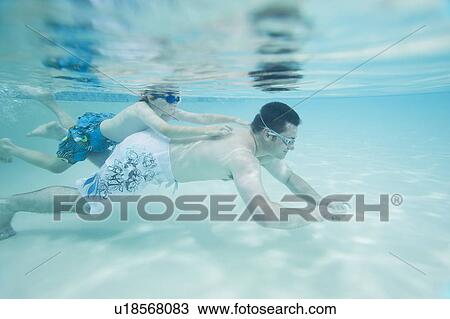 Boy swimming on father’s back underwater View Large Photo Image Stock Image - Boy swimming on father’s back underwater. Fotosearch