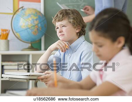 Boy thinking at school desk View Large Photo Image Stock Photograph - Boy thinking at school desk. Fotosearch