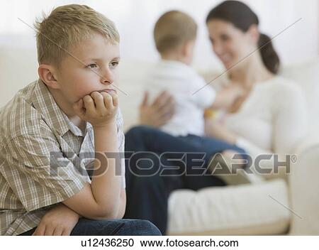 Stock Image - Boy thinking in front of mother and baby. Fotosearch