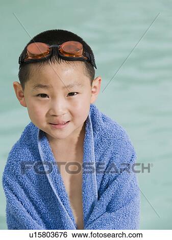 Stock Photograph - Boy wrapped in towel posing in front of swimming pool. Fotosearch