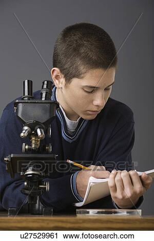 Boy writing in notebook next to microscope View Large Photo Image Stock Image - Boy writing in notebook next to microscope. Fotosearch