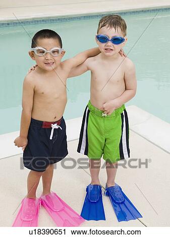 Stock Image - Boys in flippers posing by swimming pool. Fotosearch