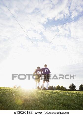 Stock Image - Boys in soccer uniforms walking on field. Fotosearch