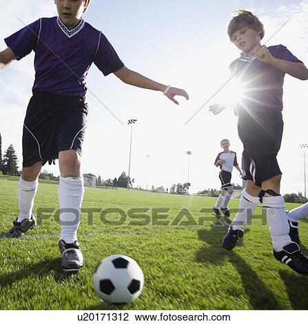 Stock Image - Boys playing competitive soccer. Fotosearch