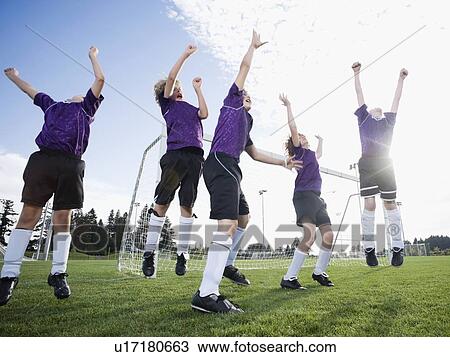 Stock Image - Boys soccer team celebrating on field. Fotosearch