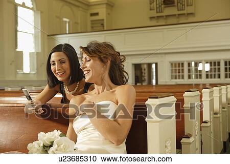 Bride and friend looking at cell phone View Large Photo Image Stock Image - Bride and friend looking at cell phone. Fotosearch