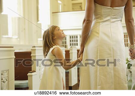Stock Photograph - Bride holding flower girl’s hand. Fotosearch