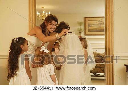 Stock Image - Bride putting veil on flower girl. Fotosearch