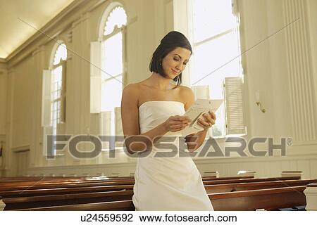 Stock Image - Bride reading letter in church. Fotosearch