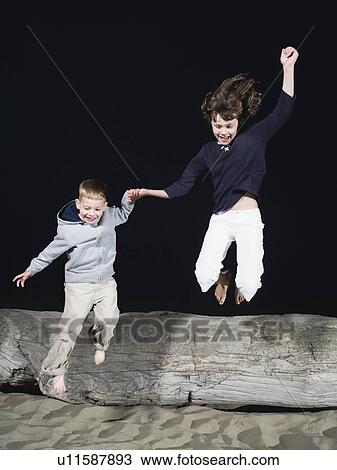 Brother and sister jumping off driftwood View Large Photo Image Stock Image - Brother and sister jumping off driftwood. Fotosearch