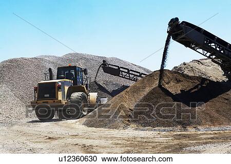 Stock Image - Bucket loader moving pile of gravel. Fotosearch