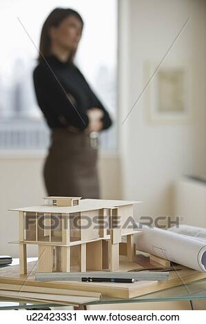 Stock Image - Building model and blueprints with architect in background. Fotosearch