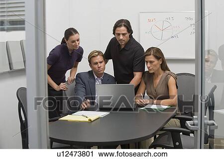 Stock Image - Business people working on laptop in meeting. Fotosearch
