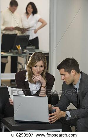 Stock Photo - Businessman and businesswoman using laptop. Fotosearch