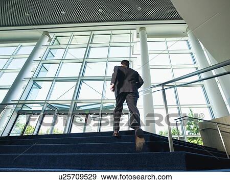 Stock Photo - Businessman ascending office building stairs. Fotosearch