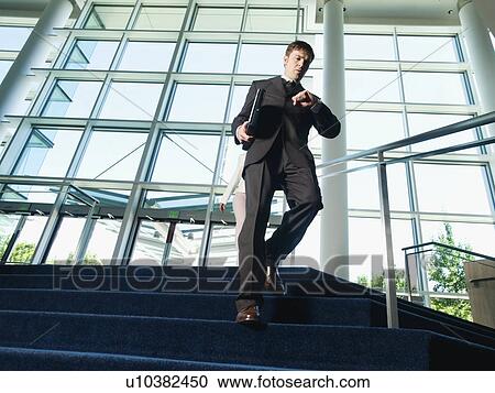 Stock Image - Businessman descending office building stairs. Fotosearch