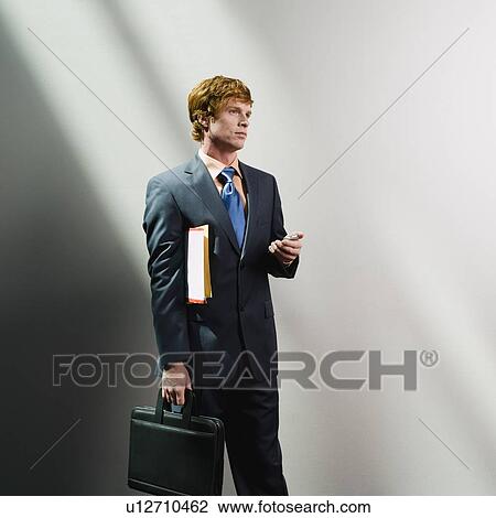 Businessman holding cell phone, files and briefcase View Large Photo Image Stock Image - Businessman holding cell phone, files and briefcase. Fotosearch