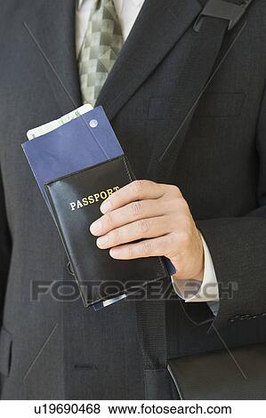 Stock Photo - Businessman holding passport and airplane ticket. Fotosearch