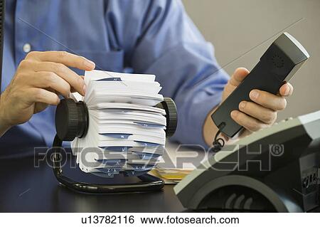 Businessman holding telephone and looking at card file View Large Photo Image Stock Photograph - Businessman holding telephone and looking at card file. Fotosearch