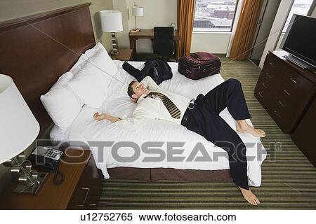 Businessman laying on hotel bed View Large Photo Image Stock Photography - Businessman laying on hotel bed. Fotosearch