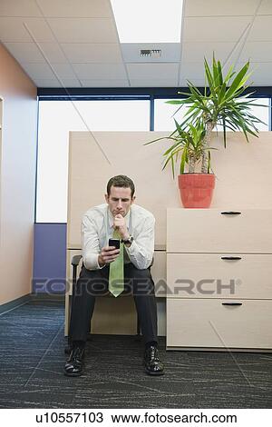 Stock Image - Businessman looking at cell phone. Fotosearch