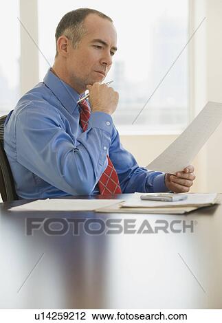 Stock Image - Businessman reading paperwork. Fotosearch