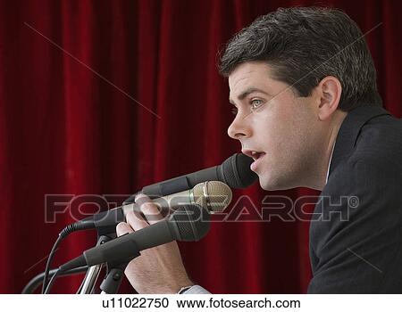 Stock Image - Businessman speaking into microphone. Fotosearch