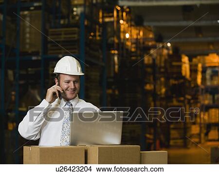 Businessman talking on cell phone in warehouse View Large Photo Image Picture - Businessman talking on cell phone in warehouse. Fotosearch